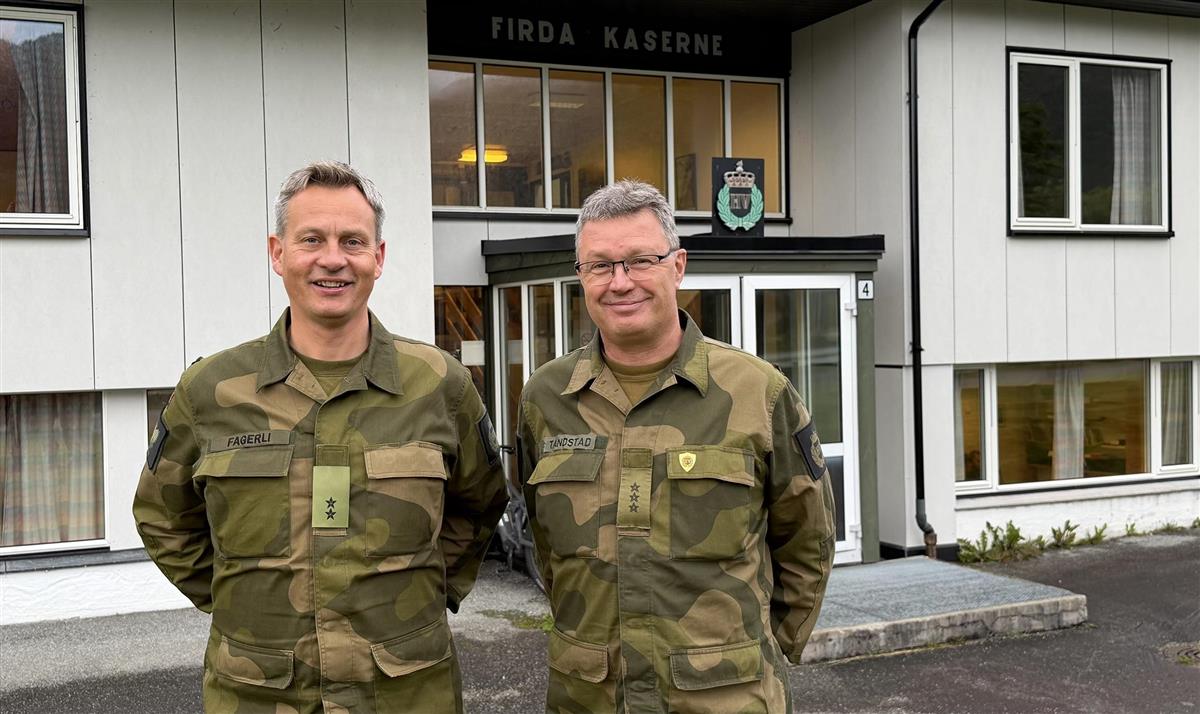 To personar i militær uniform står framfor ei bygning - Klikk for stort bilete